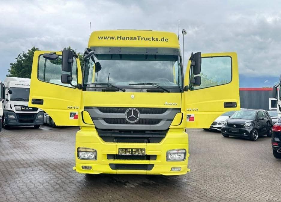 Tracteur routier jaune, portes ouvertes, sur un parc de véhicules